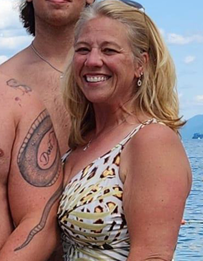 Woman smiling near water with tattooed man, related to police discovering disturbing detail about ice rink attacker family.