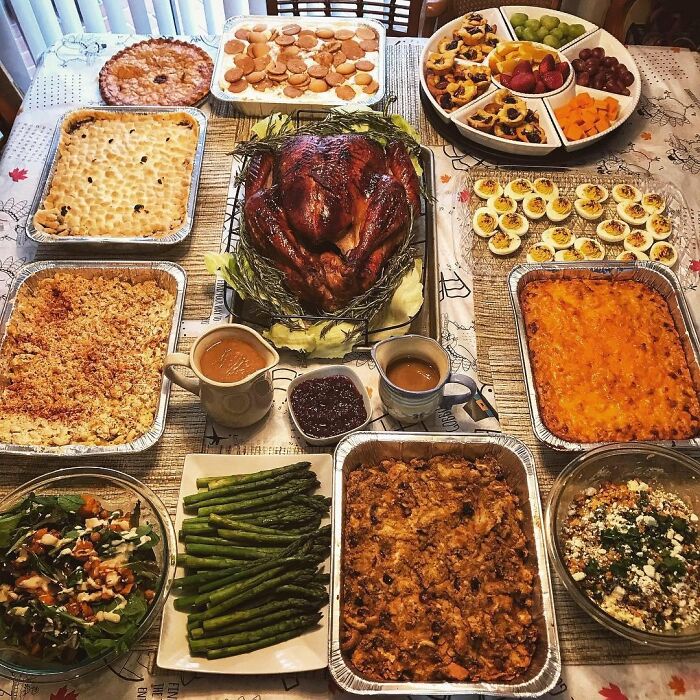 A traditional holiday feast with roasted turkey, casseroles, deviled eggs, asparagus, and assorted desserts on a table.