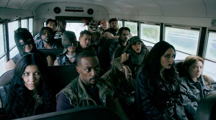 Diverse group of intense characters sitting on a bus in a dark, post-apocalyptic setting for shows like Fallout. - 3
