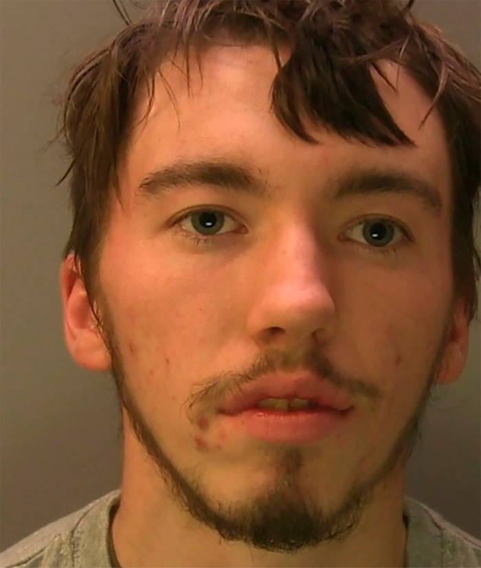Close-up of a young male student with facial hair and acne, connected to the story about blowing up sheep with fireworks.