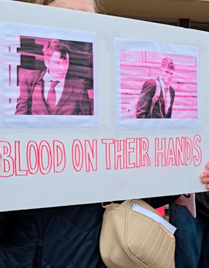 Protest sign with images of two students referring to karma and their fate after blowing up sheep with fireworks.