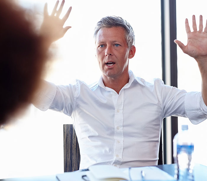 Man in white shirt raising hands, symbolizing top employee delivering record results amid excuses instead of bonus discussion.