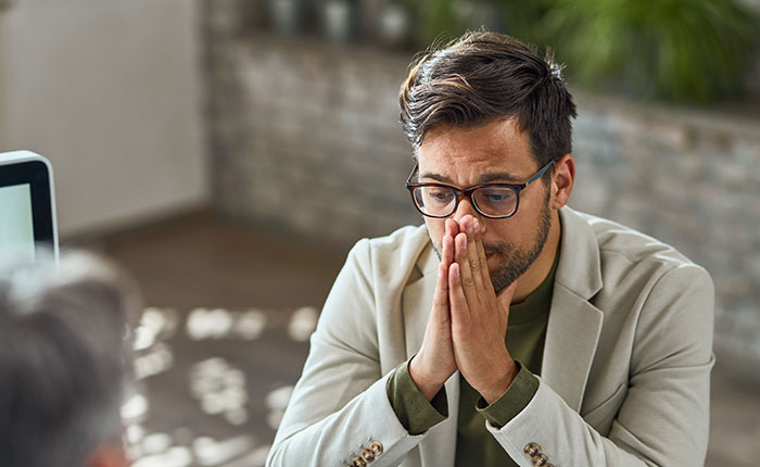 Top employee with glasses and beige blazer delivers record results, appearing stressed while discussing work with colleague.