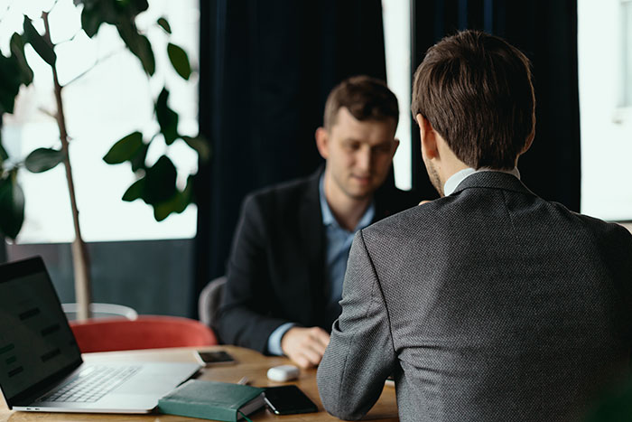 Two men in business suits having a serious discussion in an office, highlighting top employee delivering record results.