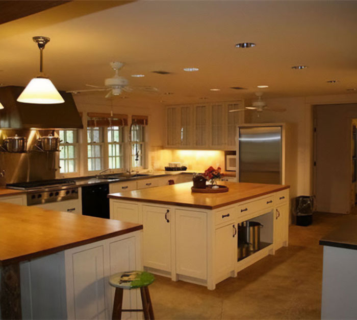 Modern kitchen with wooden countertops and white cabinets, highlighting the concept of hiring a money manager debate.