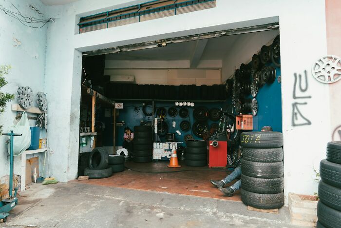 Tire shop with stacked tires and partially visible person, highlighting dangerous things often dismissed in everyday places.