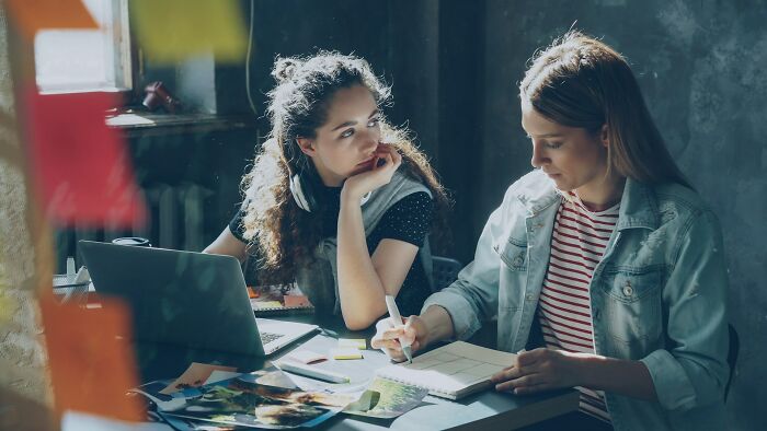 Two women sitting at a table with a laptop and notebook, illustrating stories of friendships ending before starting.