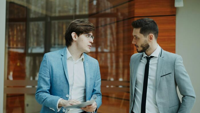 Two men in suits having a serious conversation indoors, illustrating friendships ending without even starting.