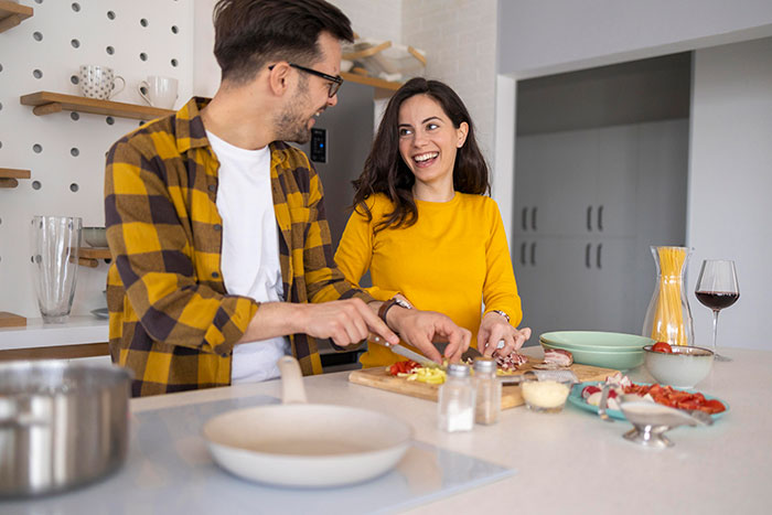 Couple in kitchen preparing food together, illustrating ways to respond when someone weaponizes their incompetence.