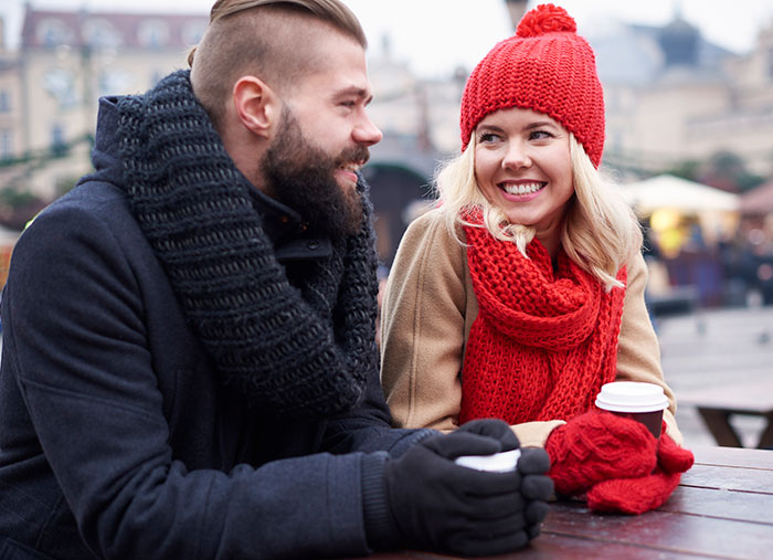 Two people in winter clothes smiling and talking outdoors, illustrating ways to respond to weaponized incompetence.