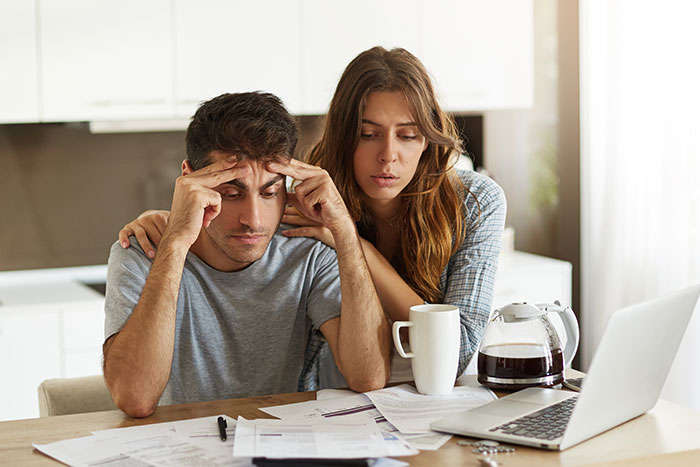 A worried couple reviewing bills at home, illustrating responses to when someone weaponizes their incompetence.
