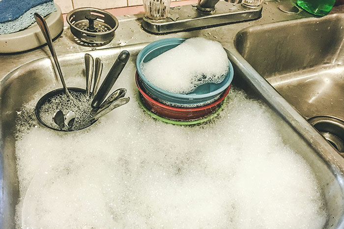 Sink filled with soapy water and dishes, illustrating the concept of responding to weaponized incompetence.