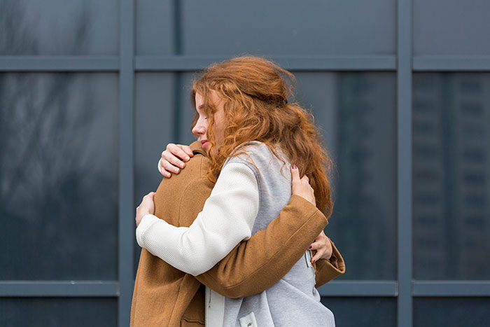 Two women hugging outside, conveying comfort and support, related to other women can't reasons for having kids.