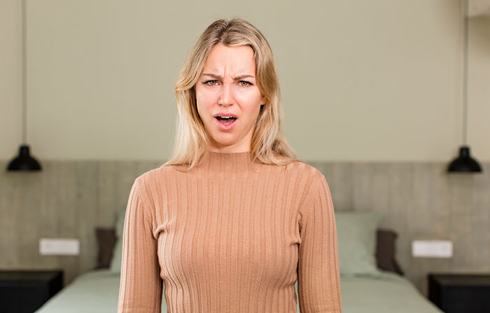 Woman in a beige sweater looking confused and skeptical indoors, expressing disbelief at ridiculous reasons to have kids.