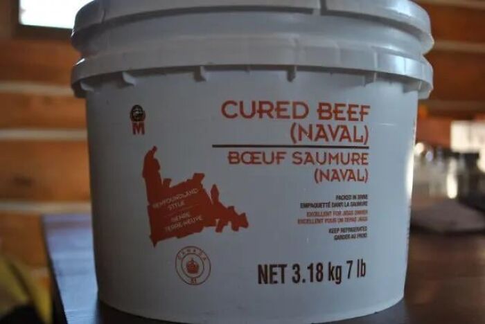 Large bucket of cured beef labeled with weight and regional style, illustrating unique food items from different countries.