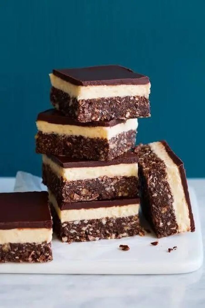Stack of layered dessert bars with chocolate and creamy filling, illustrating things people think are common everywhere.