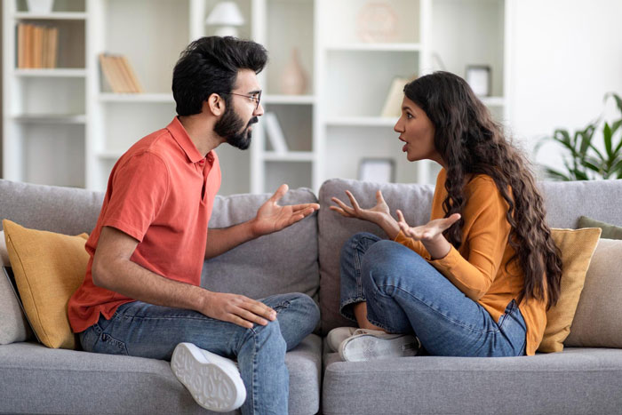 Couple having a heated argument on a couch, showing tension and frustration reflecting insecurity and relationship conflict. Couple having a heated argument on a couch, showing tension and frustration reflecting insecurity and relationship conflict.