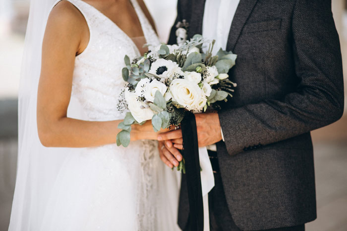 Bride and groom holding white floral bouquet at wedding, highlighting mistress-turned-wife and insecurity theme. Bride and groom holding white floral bouquet at wedding, highlighting mistress-turned-wife and insecurity theme.