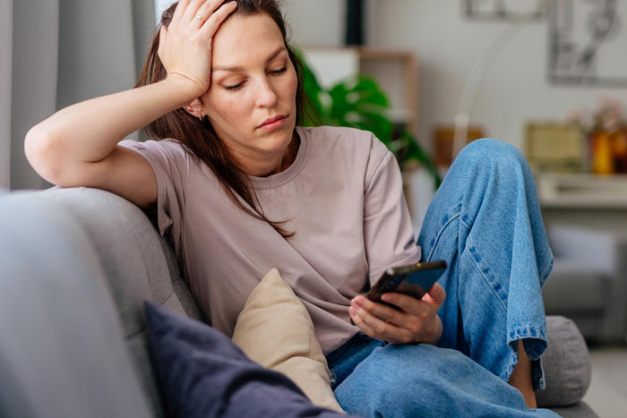 Woman looking upset and insecure on sofa holding phone, illustrating mistress-turned-wife's emotional struggle and exposed insecurity. Woman looking upset and insecure on sofa holding phone, illustrating mistress-turned-wife's emotional struggle and exposed insecurity.