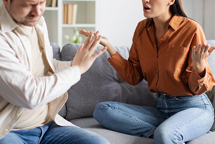 Married man and woman having a tense conversation on couch, illustrating married man texted woman he loved 15 years ago.