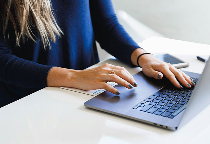 Person using a laptop with smartphone on desk, illustrating workplace incidents showing your job is not that bad.