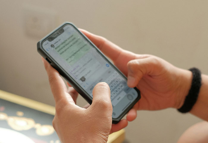Person holding smartphone typing a message, illustrating unhinged workplace incidents and unusual job moments.