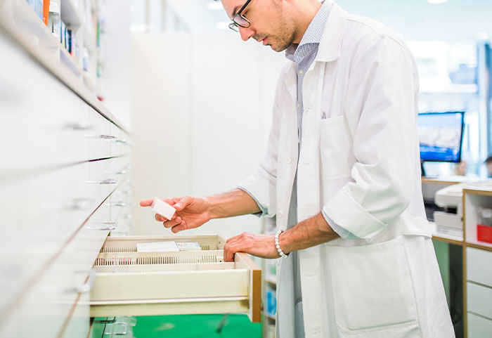 Pharmacist sorting medication in a pharmacy, illustrating unhinged workplace incidents that prove your job is not that bad.