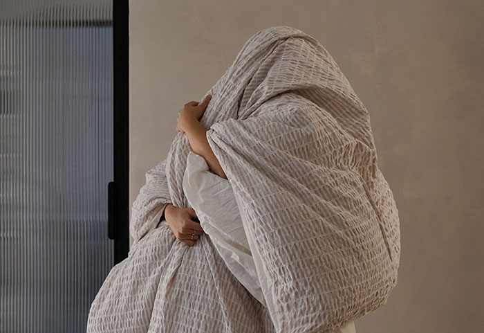 Person wrapped in a large blanket inside an office, illustrating unhinged workplace incidents and unusual job moments.