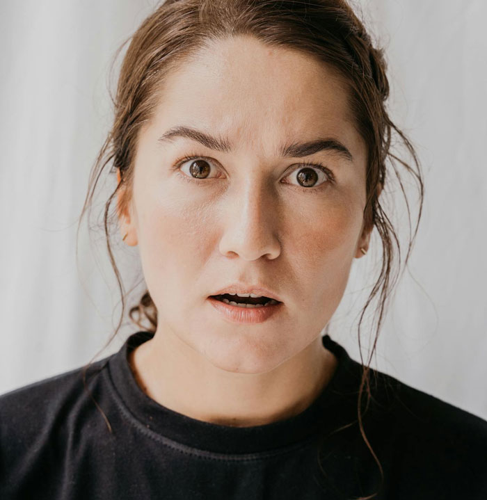 Woman looking shocked and concerned, reacting to a drunk boyfriend acting like a jerk in a tense moment.