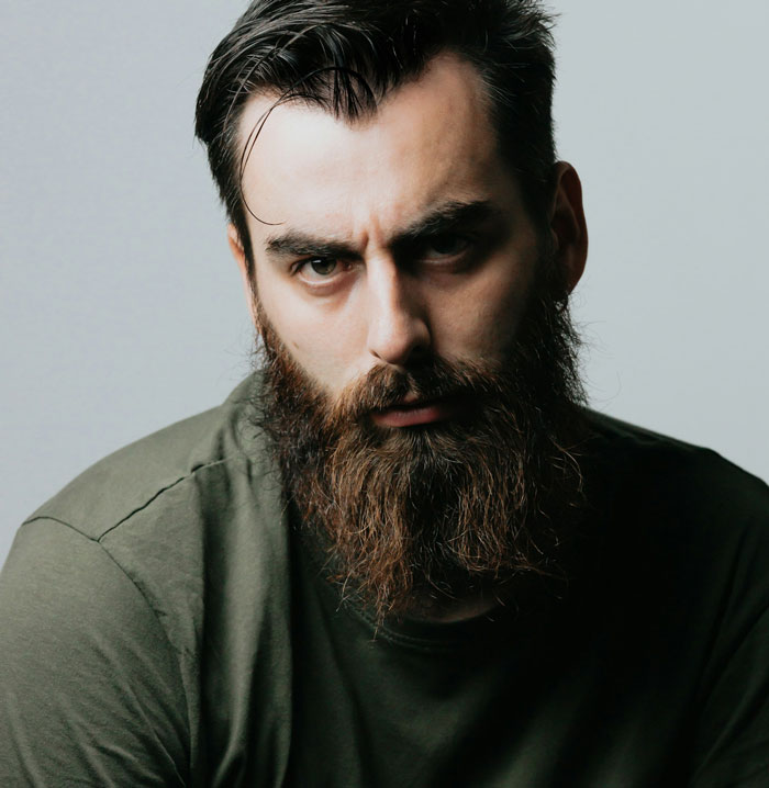 Close-up portrait of a bearded man with serious expression, illustrating a drunk boyfriend acting like a jerk.