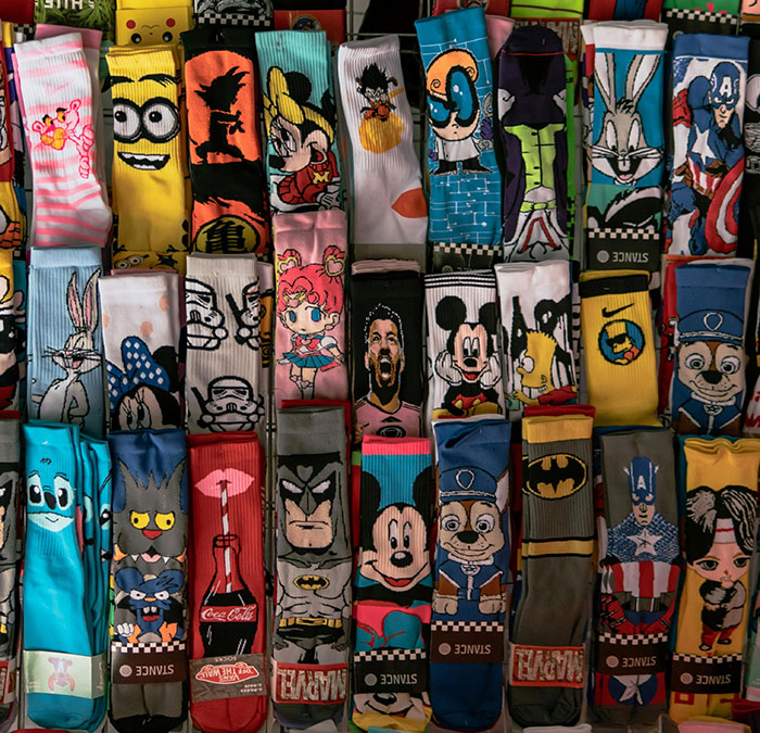 Colorful fun sock collection featuring various cartoon and pop culture characters neatly arranged in rows.