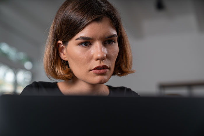 Woman checking suspicious boyfriend's past on laptop, looking horrified after discovering he is already married.