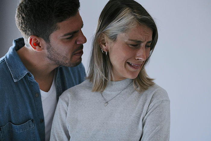 Woman upset and crying while a man leans in close, depicting a woman leave fiance over boyfriend conflict.
