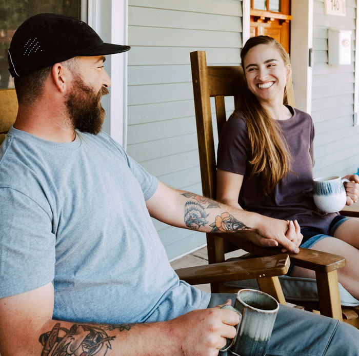 Couple holding hands on a porch, with the guy showing frustration as his girlfriend refuses to wear dresses.