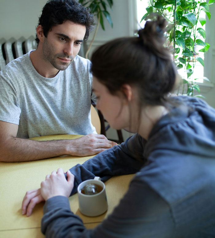 Man looks upset while woman refuses to wear dresses even for a wedding during a tense conversation at home.