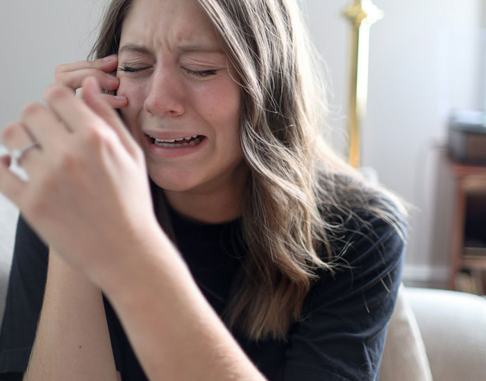 Woman crying and upset indoors, expressing distress related to parenting and family conflict involving her brother.