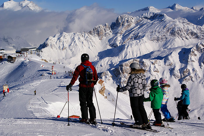 Family skiing on snowy mountain slopes with stunning peaks in the background, highlighting ski pass challenges.