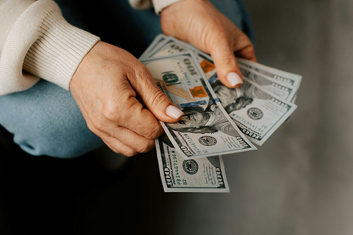 Woman counting cash in hands symbolizing financial stress over ski pass for her son.
