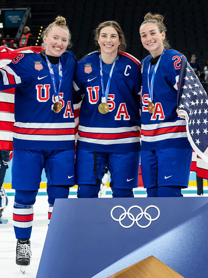 US Olympics women's hockey team players celebrating with gold medals on ice after winning Olympic event. US Olympics women's hockey team players celebrating with gold medals on ice after winning Olympic event.