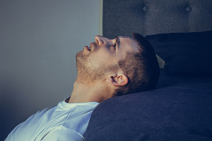 Man lying back on couch with eyes closed, reflecting after getting fired over a crude drawing and learning her tragic story.