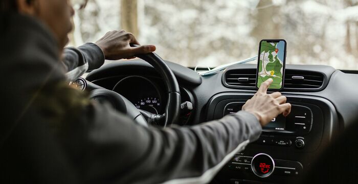 Driver using a smartphone GPS for navigation inside a car, illustrating an example of outrageous entitlement behavior.