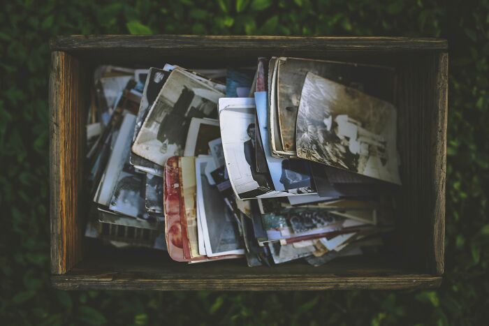 A wooden box filled with old black and white photos, evoking memories for the Would You Still Do It poll.