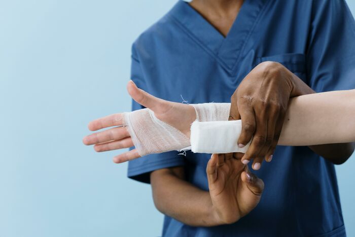 Medical professional in blue scrubs wrapping a patient's wrist with gauze for the Would You Still Do It poll concept.