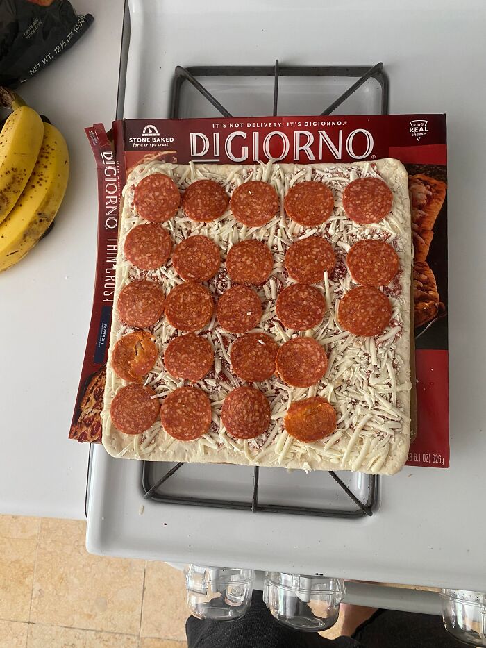 Uncooked Digiorno pepperoni pizza on a stove next to bananas, illustrating funny and harmless conspiracy theories concept.