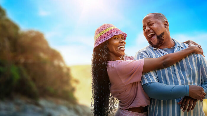 A joyful couple outdoors laughing and embracing, enjoying a sunny day perfect for watching the latest Netflix releases.