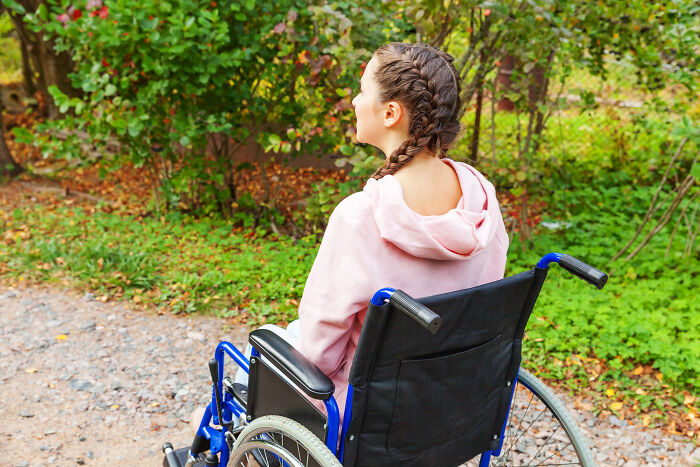 Young woman in a wheelchair outdoors, showing a display of entitlement and testing everyone's patience.