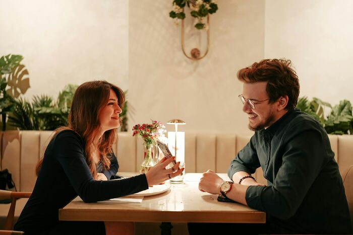 A young couple sharing a playful moment on a date in a cozy restaurant, highlighting wild dating experiences.
