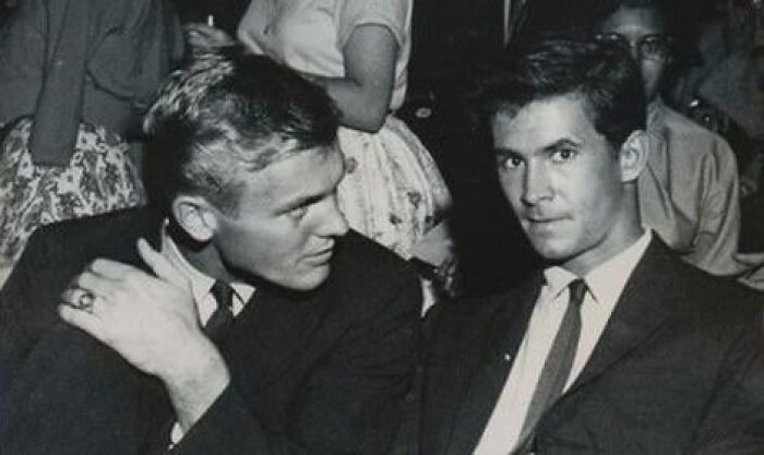 Two young men in vintage suits at a social event, capturing a moment of crazy things people did for love.