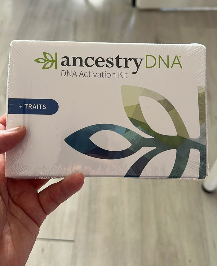 Hand holding an ancestry DNA activation kit box related to secret DNA testing of grandkid situations.