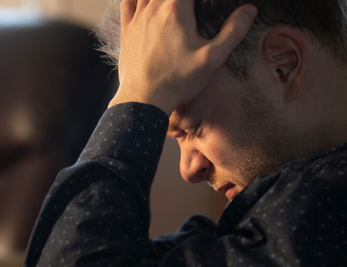 Stressed man holding his head, reflecting on relationship struggles while people online express concern about their kid.